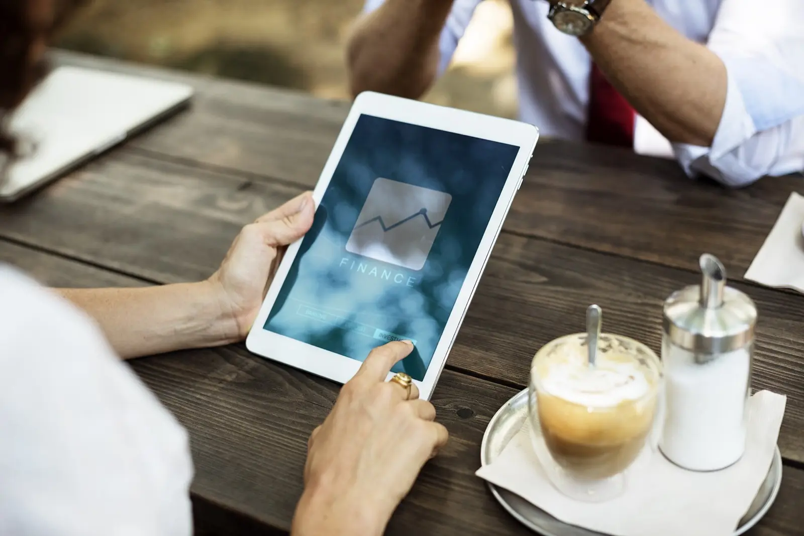 Mains tenant une tablette affichant un graphique, à côté d’un café