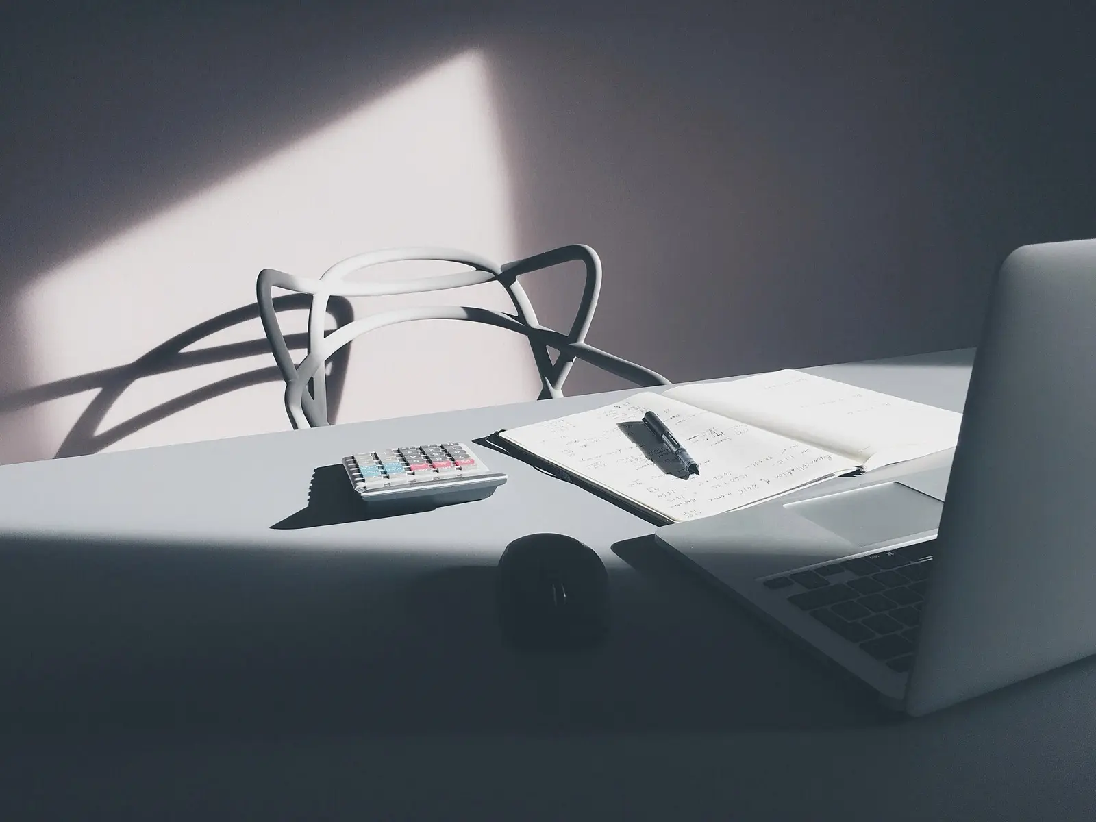 Bureau avec un ordinateur portable, une calculatrice et des documents annotés
